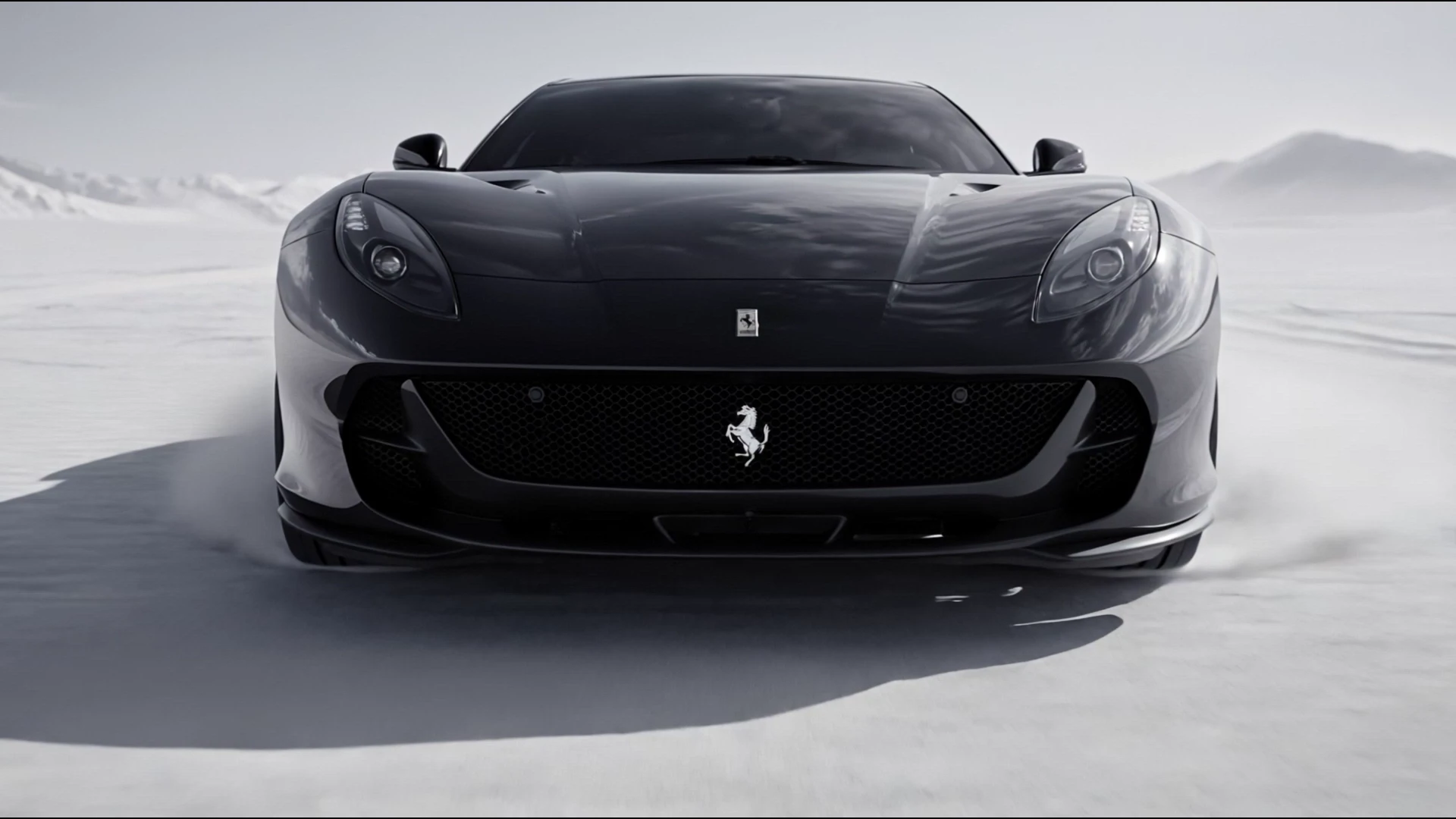 A frontal view of the Ferrari with its prancing-horse badge clearly visible on the grille, framed against the desert landscape.